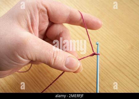 Making crochet necklace, With the lip of the hook, pull the yarn through. the loop on the shank of the hook, and tighten, making first chain of foundation chain Stock Photo