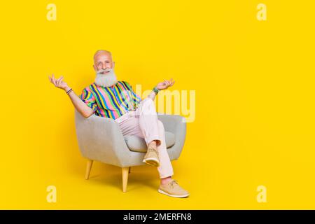 Full body photo of funky cheerful granddad sit armchair communicate say tell isolated on yellow color background Stock Photo