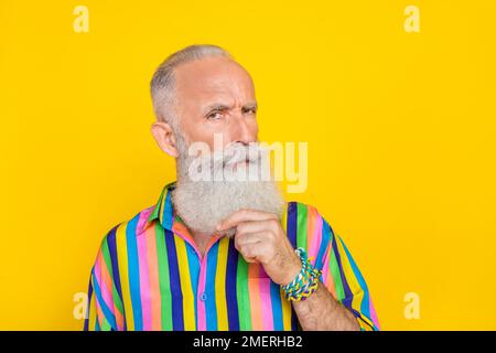 Photo of serious handsome nice man with white beard dressed striped shirt fingers touching beard isolated on yellow color background Stock Photo