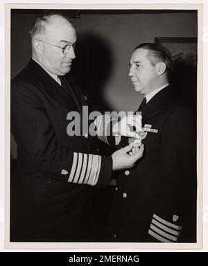 Coast Guard Captain of Washington, DC, Awarded Legion of Merit. Admiral Joseph F. Farley, USCG, Commandant of the Coast Guard, presents the Legion of Merit to Captain Frank T. Kenner, USCG, of Washington, D.C., Chief of the Program Planning Division at Coast Guard Headquarters. The medal was awarded to Captain Kenner by General Headquarters of the U.S. Army Forces in the Pacific, for his exceptionally meritorious services in New Guinea and the Philippines as Commander of the Coast Guard Army Detachment there. In manning and operating more than two hundred Army vessels, repairing and maintainin Stock Photo