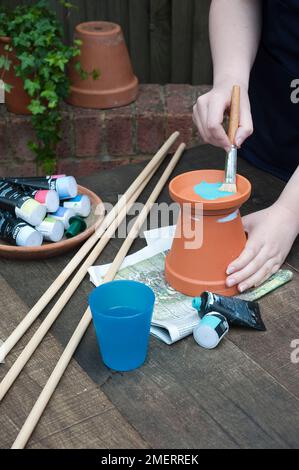Painting drip tray blue, table containing cane, paints and water Stock Photo