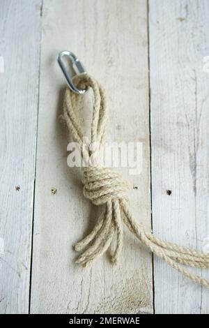 Making plant pot mobile, four ends of rope gathered tied in strong knot attached to karabiner or metal loop Stock Photo