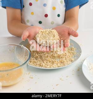 Boy breadcrumbing a fishcake Stock Photo