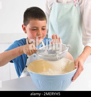 Sieving flour into a mixing bowl, 7 years Stock Photo