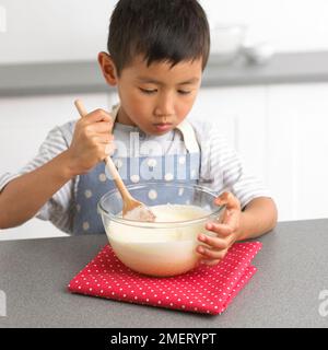 Making white chocolate truffles, Boy mixing white chocolate mixture, 4 years Stock Photo