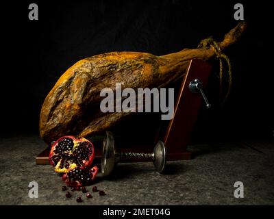 whole leg of jamon with pomegranate on black background Stock Photo