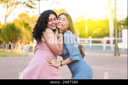 Two female friends hugging in front outdoors, girl friends hugging and enjoying life, women friendship concept Stock Photo