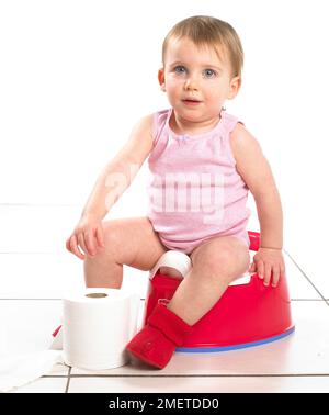 Girl wearing red socks and pink top sitting on red potty with roll of toilet paper in front, 19 months Girl wearing red socks and pink top sitting on red potty with roll of toilet paper in front, 19 months