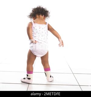 Girl wearing pants, vest and slippers, back view, 16 months Stock Photo