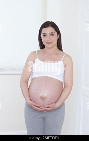 Heavily pregnant woman holding her belly Stock Photo