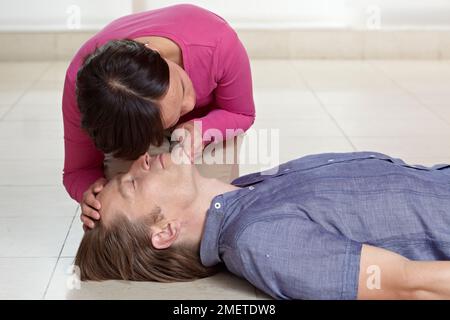First aid treatment, giving CPR, checking breathing, supporting head of casualty Stock Photo