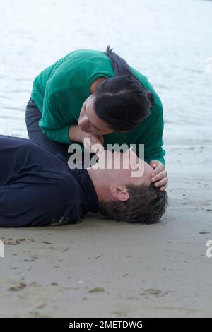First aid medical check and treatment of drowned person, checking breathing, giving CPR Stock Photo