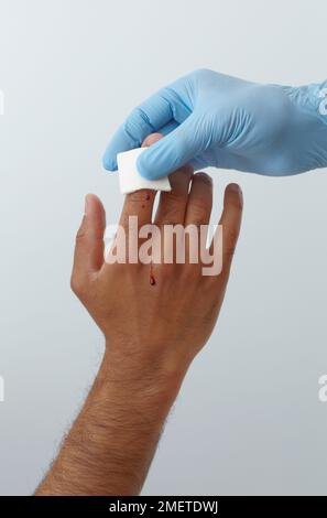 First aid treatment of finger injury, holding gauze pad on wound Stock Photo