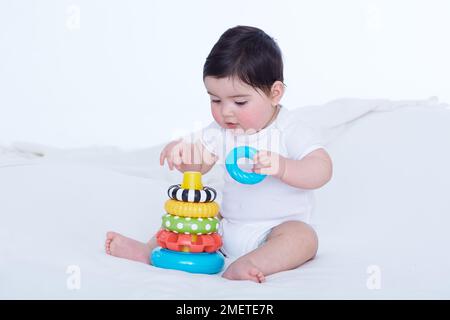 Baby girl (40 weeks) playing with plastic ring toy Stock Photo