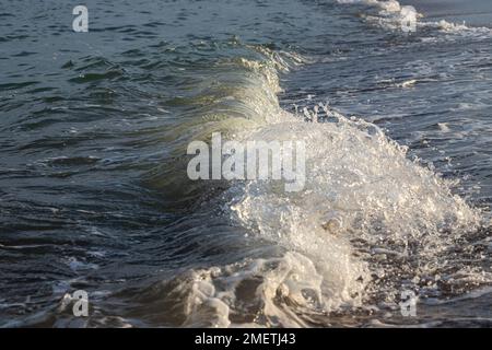 Sea waves crash against large rocks on the shore, forming large splashes.. Stock Photo