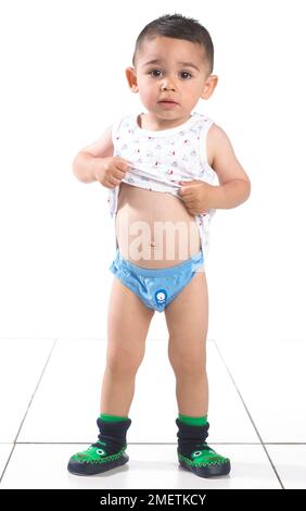 Boy wearing vest, pants and slippers, 15 months Stock Photo