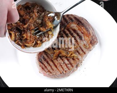 Topping grilled steak with home-made onion marmalade Stock Photo