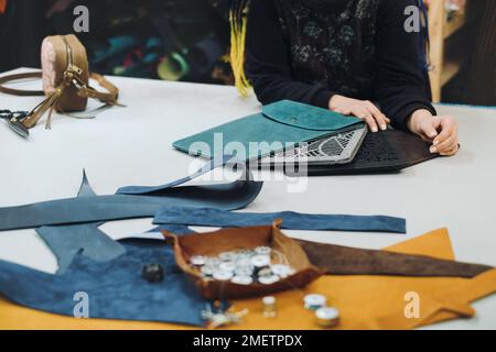 Eco leather laptop cases production. Close up of female tailor working with eco leather textile at workshop. Upcycling design concept. Copy space Stock Photo