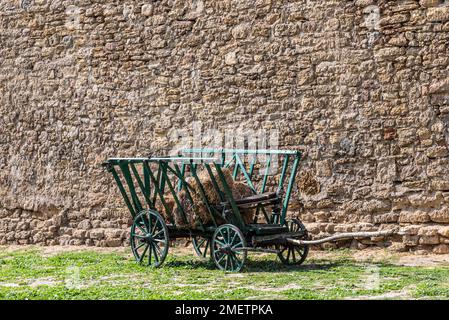 An old wooden cart for horses against a brick wall. Stock Photo