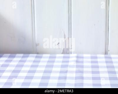 Table covered with checked tablecloth against wood wall Stock Photo
