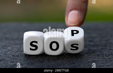 Hand turns dice and changes the abbreviation SOS (save our souls) to SOP (standard operating procedure). Symbol for getting help. Stock Photo
