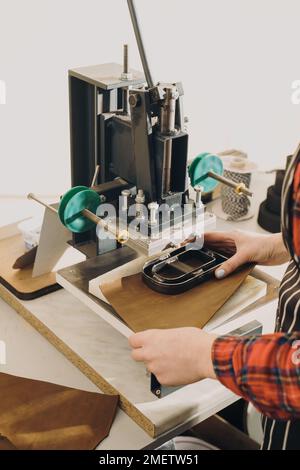 Molds for cutting leather. Cropped view of the woman hands holding leather and cutting it with special press machine. Tailoring and handicraft concept Stock Photo