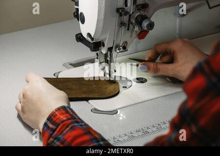 Tailor sewing at workplace. Woman hands sewing on machine at workshop. Tailoring concept. Close-up of needle and thread in female hands Stock Photo