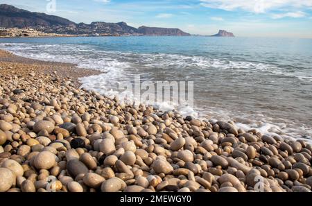 Alfaz del Pi beach with its stones in the foreground getting wet with the sea, Costa Blanca, Spain Stock Photo