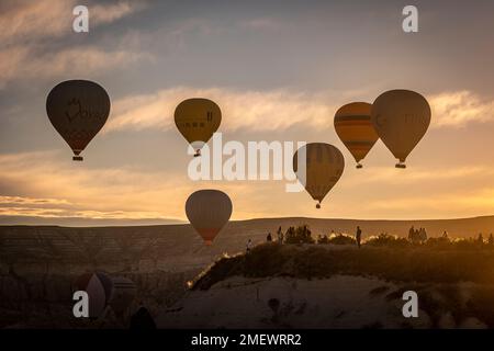 GOREME/TURKEY - June 27, 2022: Hot air balloons fly at dawn over the hills of Goreme. Stock Photo