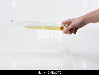 Cooking oil being poured from a glass bottle Stock Photo