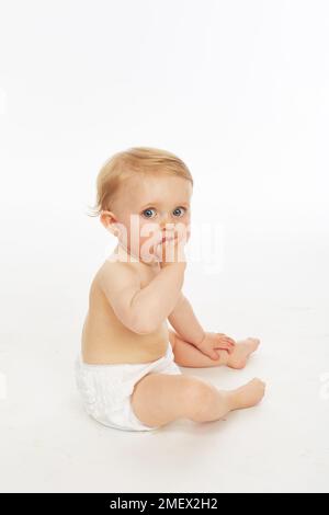 Baby in nappy sitting  (Model age - 9 months) Stock Photo