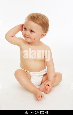 Baby in nappy sitting  (Model age - 9 months) Stock Photo