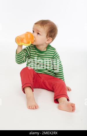 Little boy in green stripey top with cup (Model age - 22 months) Stock Photo