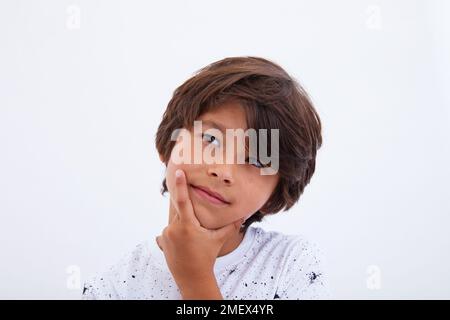 Boy think looking up, hold hand on chin Stock Photo