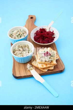 Smoked mackrel pate in ramekins on chopping board with beetroot and crackers Stock Photo