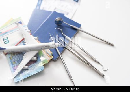 An Overhead View Of Dental Tools On Euro Notes, passport toy, airplane Stock Photo