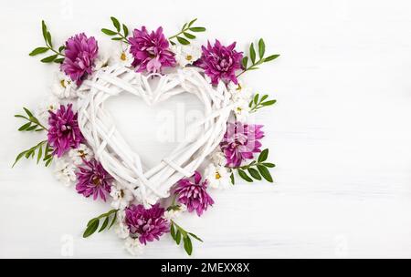 Beautiful spring flowers on white wooden background. Festive floral composition with heart from wooden branches. Valentine's day or mother's day conce Stock Photo