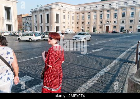 Woman looking to cross the road in a street scene in Rome, Italy Stock Photo