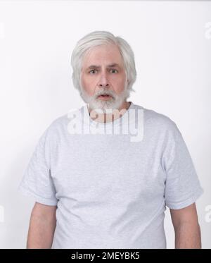 Vertical shot of a white haired old man looking confused.  White background.  Standing from the waist up.  Lots of copy space. Stock Photo