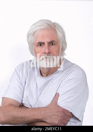 Vertical shot of an angry looking old man with white hair on a white background. Standing from the waist up. Stock Photo