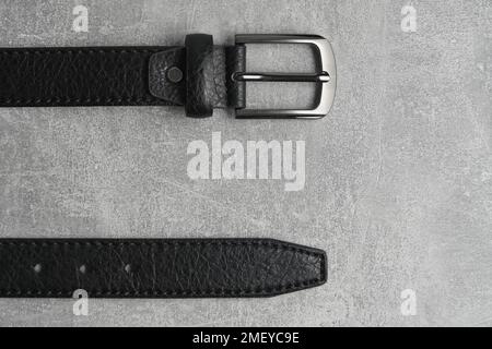 Black men leather belt with metal badge gray concrete background Stock Photo