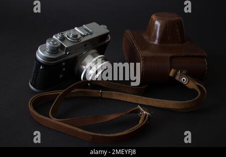 Camera and case 24.01.2023 Bialystok Poland. Photos of camera and leather case on black background. Stock Photo