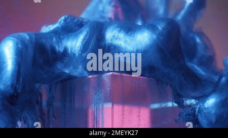 Paint drop glass cube ink water blue fluid on pink Stock Photo