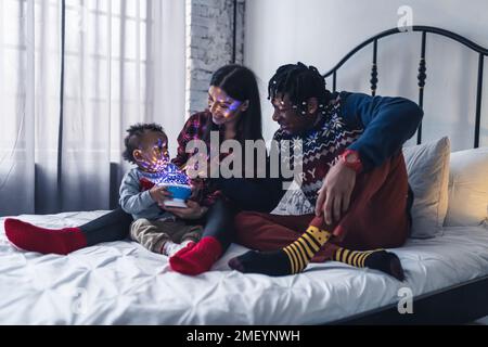 Multiracial parents playing with their toddler son on a bed. High quality photo Stock Photo
