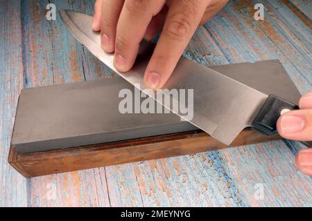 https://l450v.alamy.com/450v/2meynyg/hand-of-a-man-sharpening-a-knife-on-a-faded-wooden-table-2meynyg.jpg