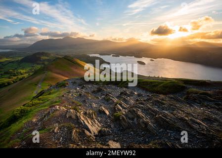 Morning golden sunlight breaking through clouds on horizon seen from Catbells overlooking Derwentwater in The Lake District, UK. Stock Photo
