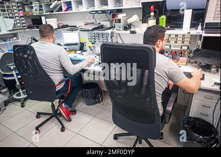 The employees in the workshop do their daily work. A workbench full of various tools and items needed to repair electrical appliances Stock Photo