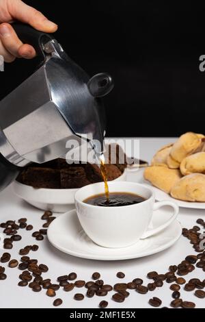 The process of pouring coffee from a geyser moka coffee maker into a white cup Stock Photo