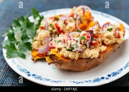 Sweet potatoes loaded with chickpea hummus and tabouleh couscous. Stock Photo