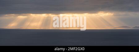 Breathtaking rays of sunlight braking through dark and moody clouds over the Outer Hebrides, Scotland, UK. Stock Photo